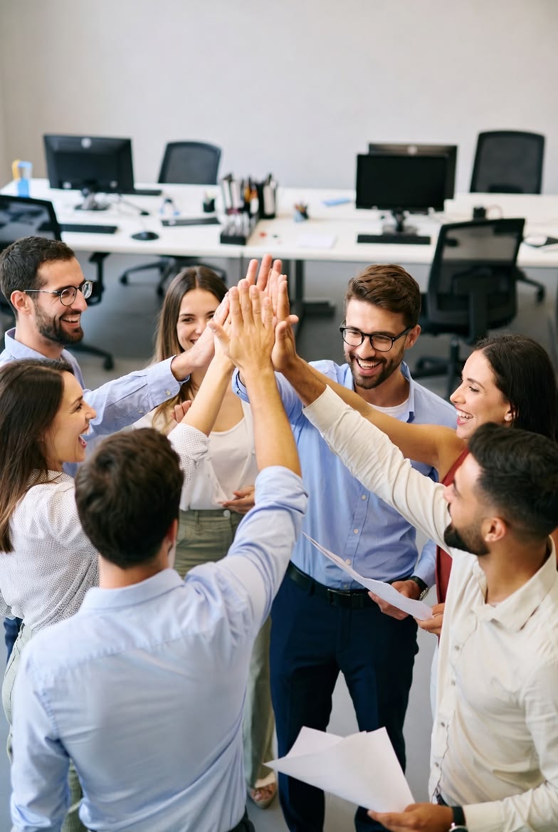 Equipo celebrando con un choque de manos en la oficina